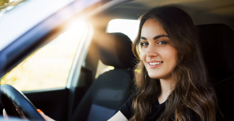A student sits behind the wheel of their car.