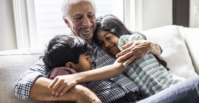 A grandfather cuddling with his grandchildren on a couch