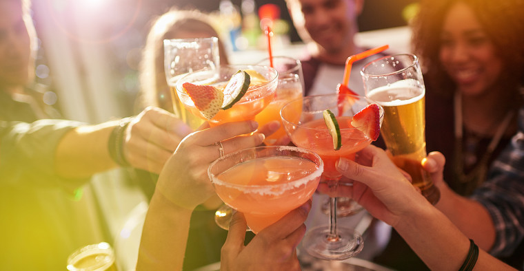 A group of people toasting with their drinks at a nightclub
