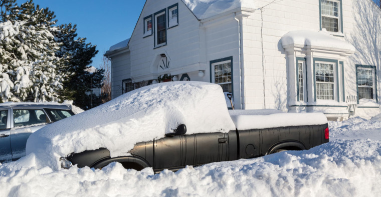 A house and truck after a heavy snowfall.