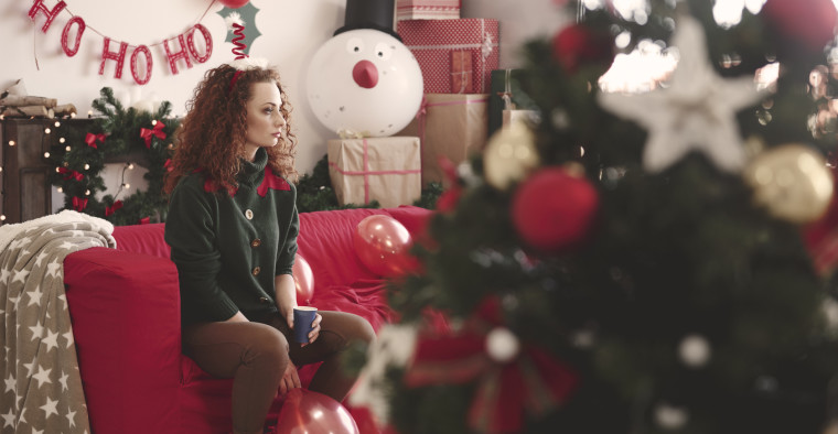A woman sits alone on her couch at Christmas.