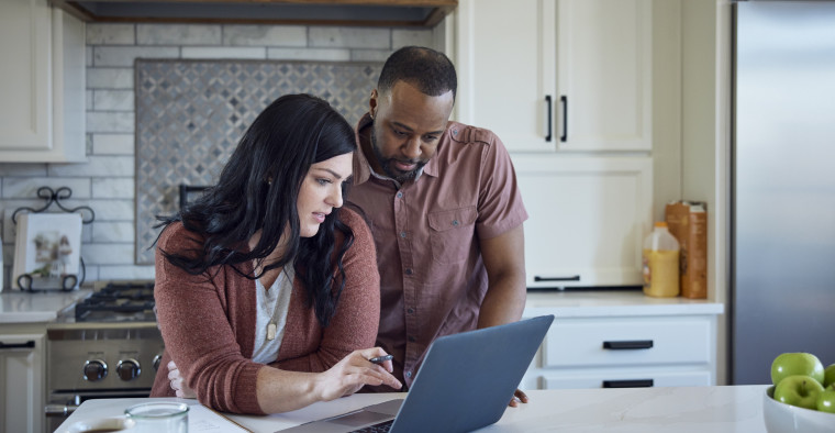 A couple shops for auto insurance on their laptop.