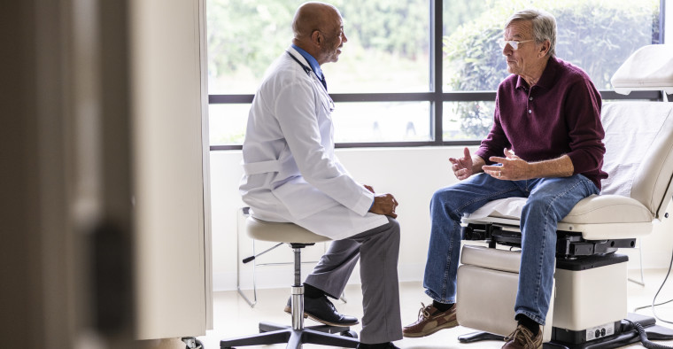 A male doctor talking with a senior male patient