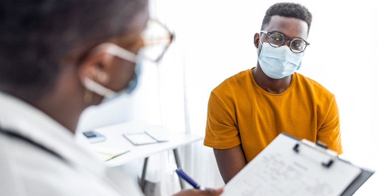 A doctor with a clipboard speaking to a patient.