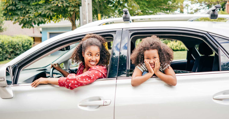 A mother and her giggling daughter in the car.
