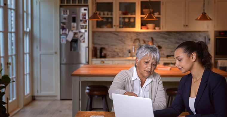 Mother and daughter reviewing documents on a laptop.