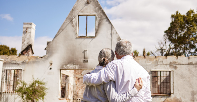 A couple looks at their damaged home.