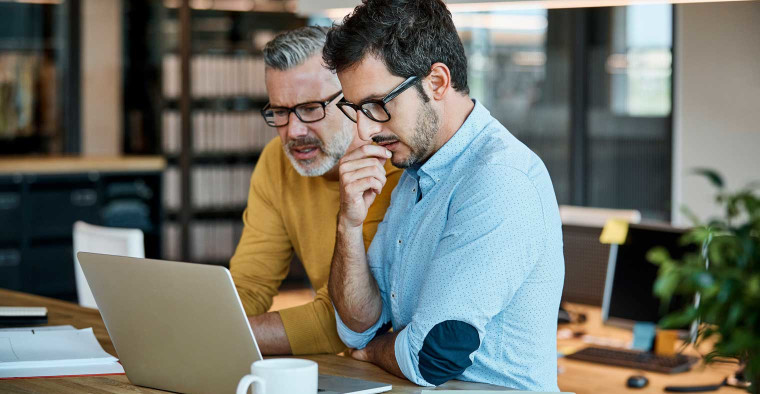 Two office workers looking at a computer