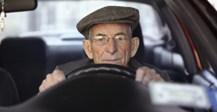 An older man drives a car.