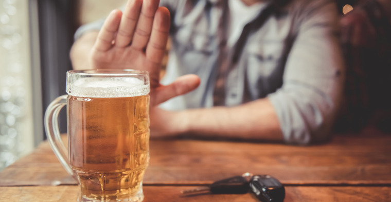 A man refusing beer while sitting next to keys.