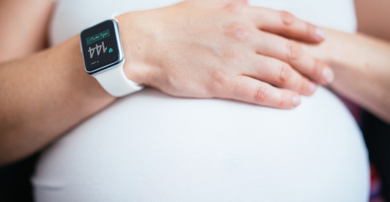 A pregnant woman wearing a smartwatch