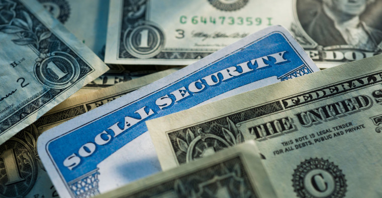 A Social Security card is covered by dollar bills.