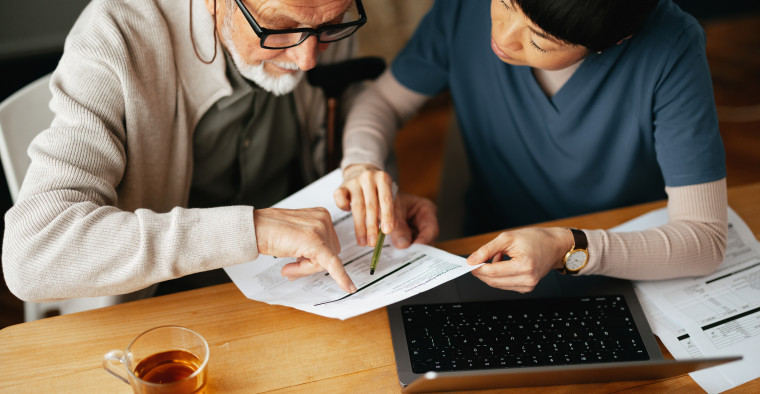 A senior man reviewing paperwork with a nurse