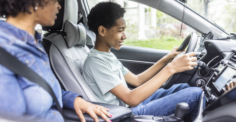 Teenage boy driving a car with his mother in the passenger seat