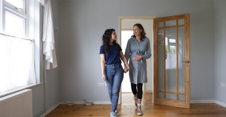 Two women walking into their house holding hands