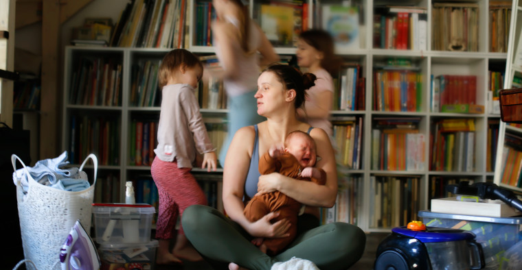 A stressed mom holding her baby with older children behind her