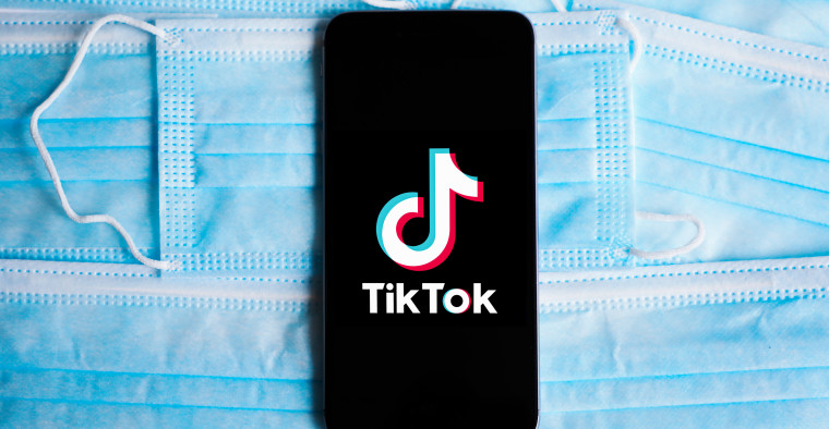 The TikTok logo is displayed on a mobile phone screen photographed on surgical masks.