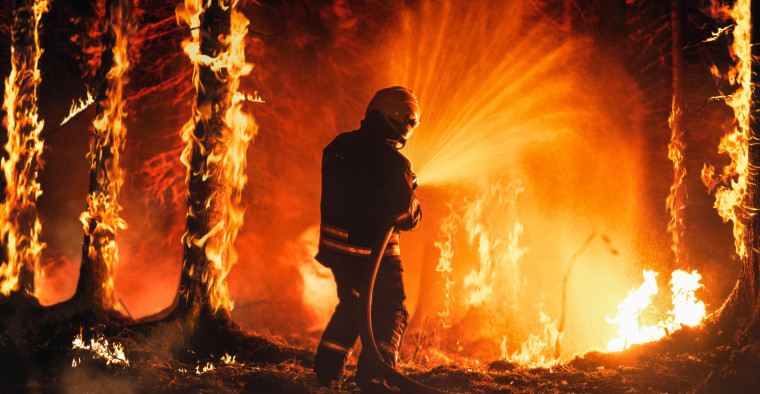 A firefighter sprays water at a wildfire.