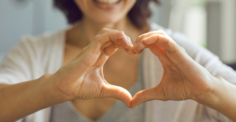 A woman makes a heart shape with her hands.