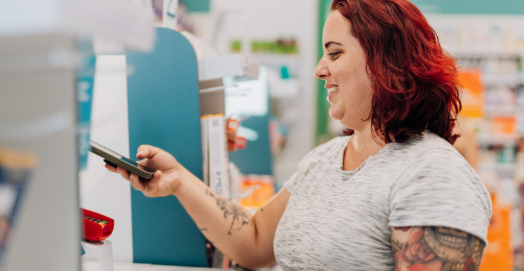 Plus size woman at payment counter with smartphone