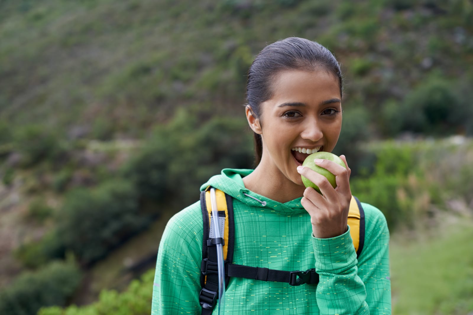 Woman is eating an apple on her hike