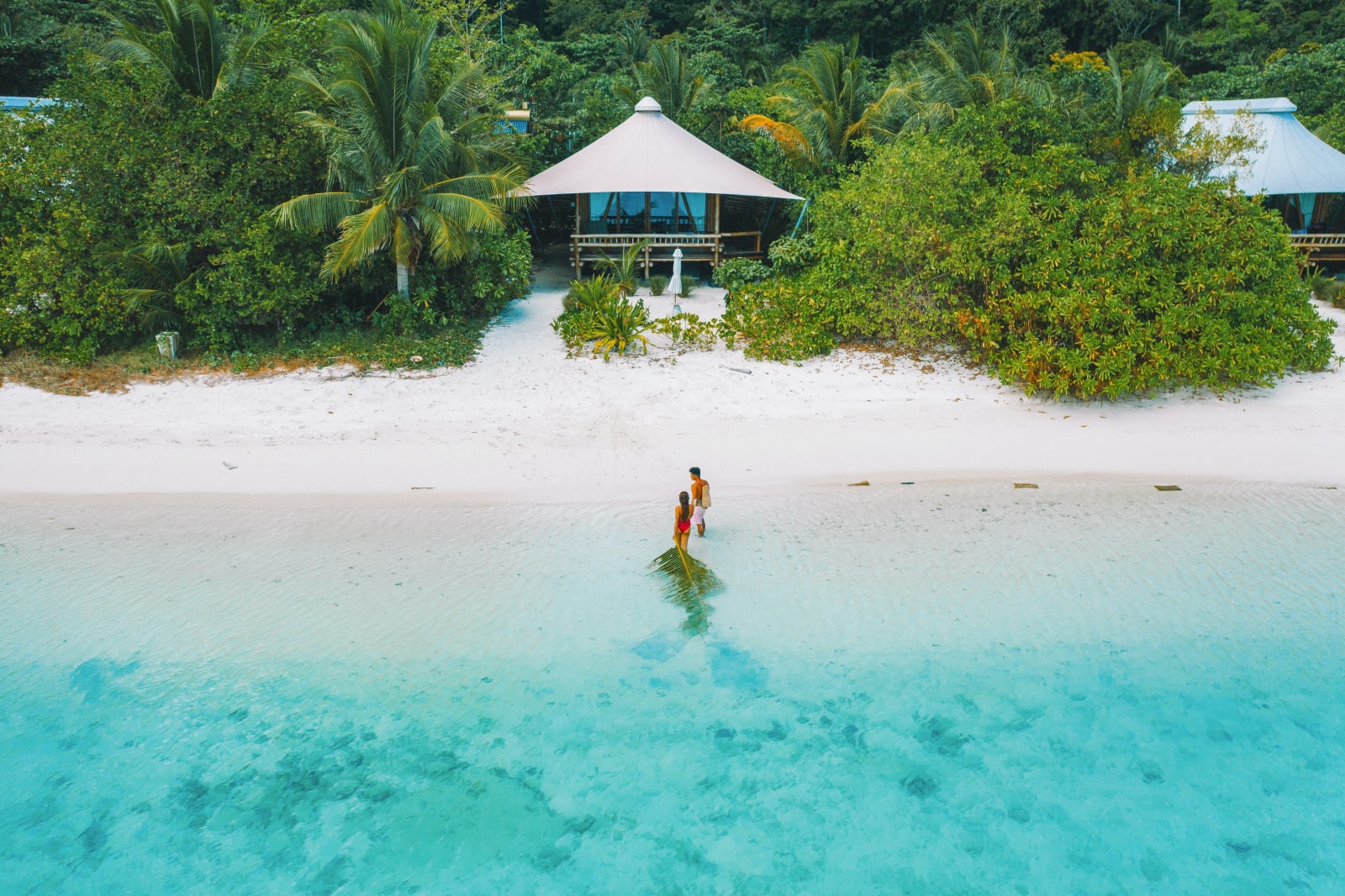 A couple on the shore of a beach with two beach houses