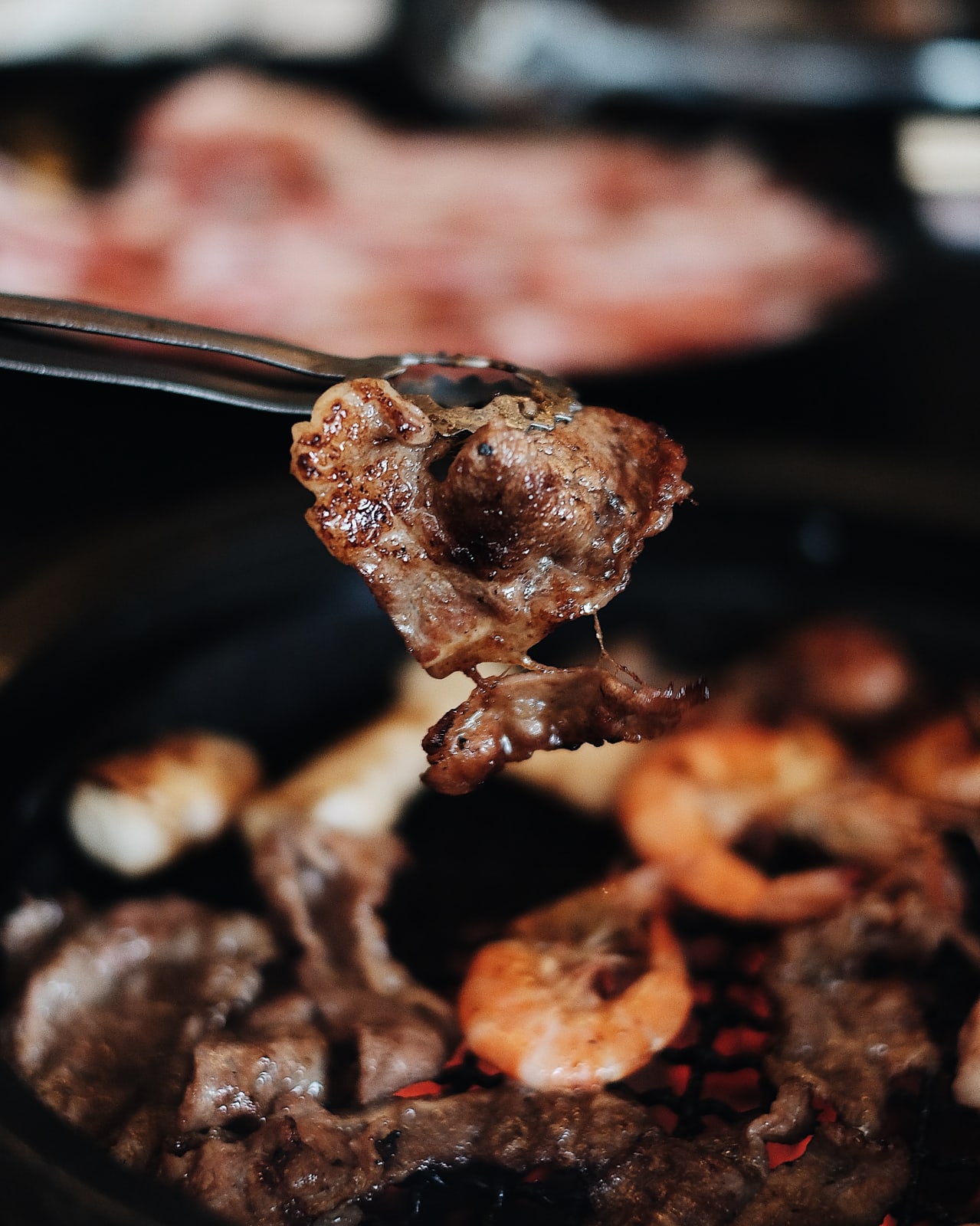 Picture of a piece of meat at korean barbeque being cooked