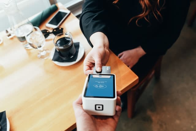 Woman using a credit card machine in a cafe