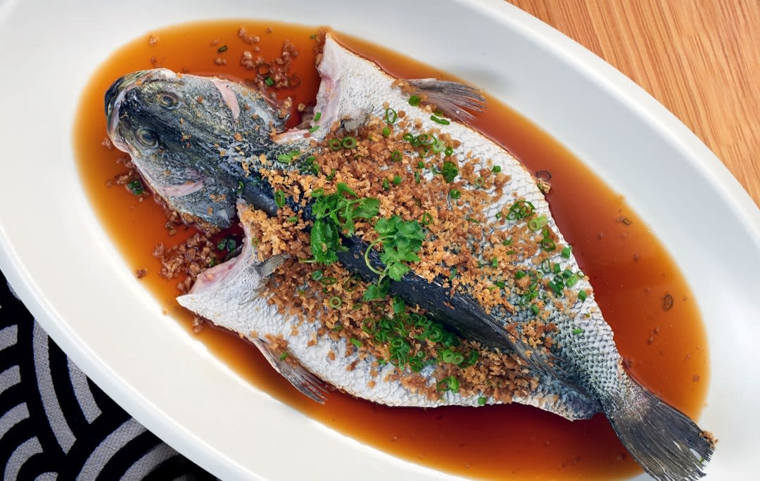 Steamed fish based in a brown sauce with crispy bits and parsley garnishing the top