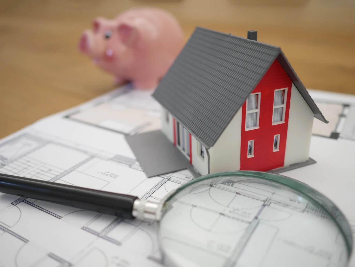 picture of a model house, piggy bank and a magnifying glass on a document