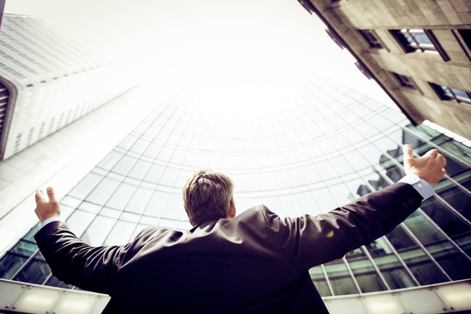 Man in a suit holding his hands up towards the sky