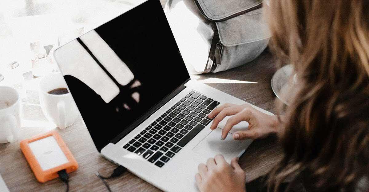 woman typing on MacBook with blank screen