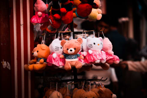 bear toy hanging with pink hello kitty toys in a retail shop