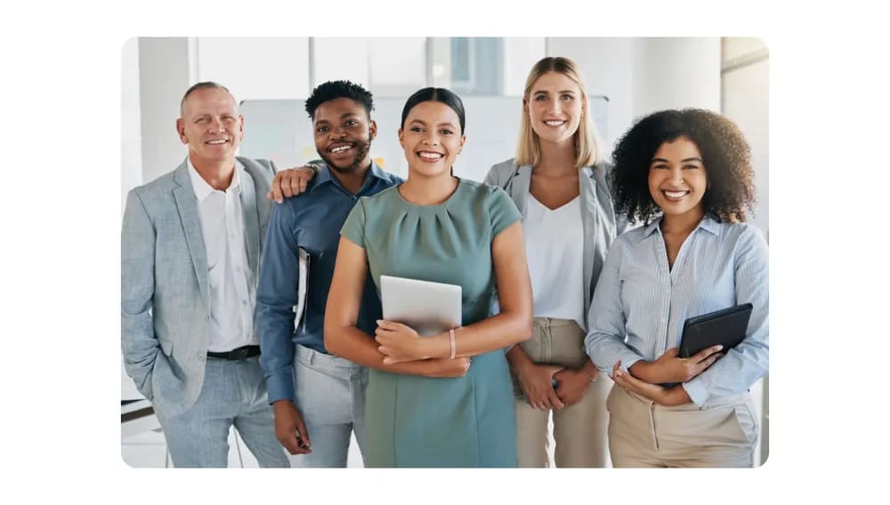 A diverse group of professionals standing together in an office, smiling confidently, representing workplace diversity and inclusion.png