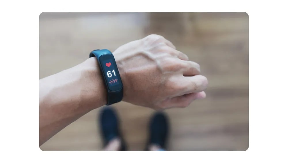 A person checking heart rate on a fitness tracker smartwatch, promoting the use of wearables for employee wellness.png