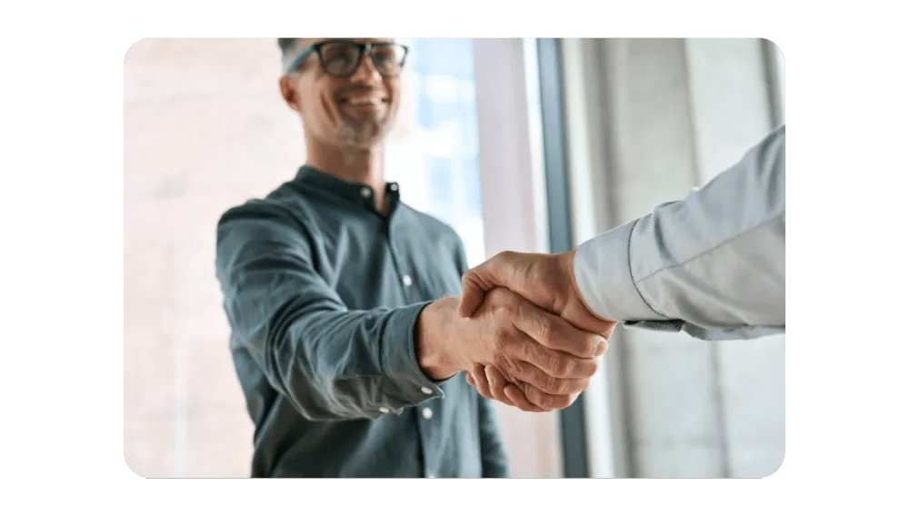 Two people shaking hands, symbolizing partnership and collaboration.