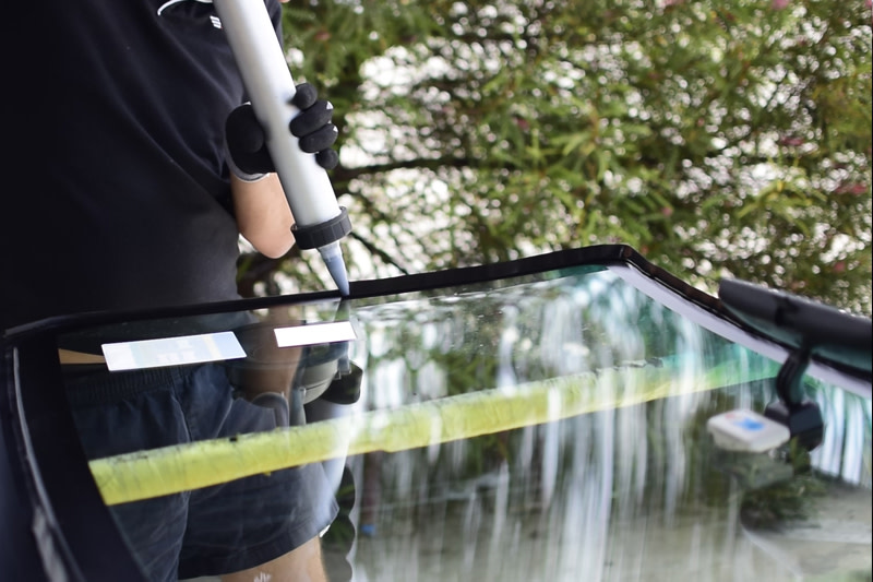 Technician applying glue on windscreen