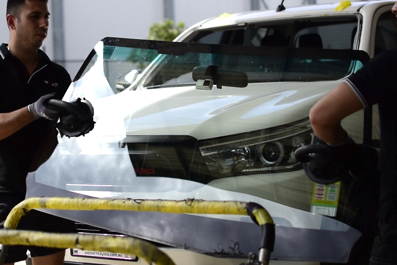 Technicians removing damaged windscreen off car