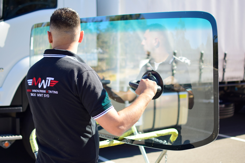 Technician installing new windscreen on truck