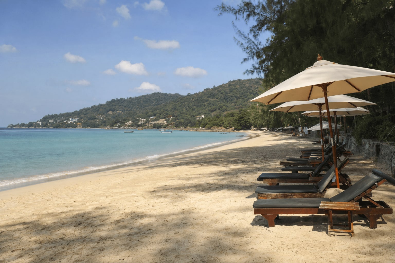 Veetrips Sandy Phuket beach with sun loungers, calm turquoise sea and green hills
