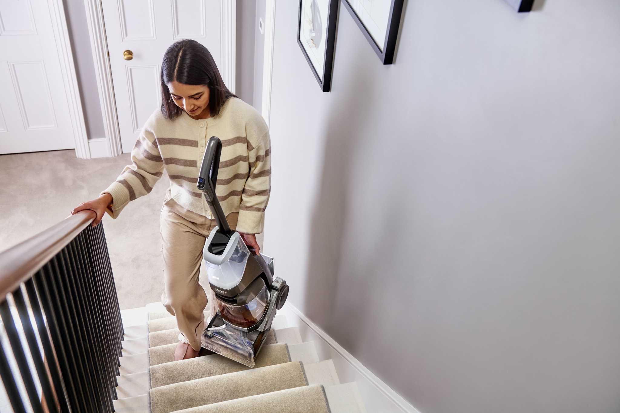 ONEPWR Compact Cordless Carpet Cleaner being carried up stairs