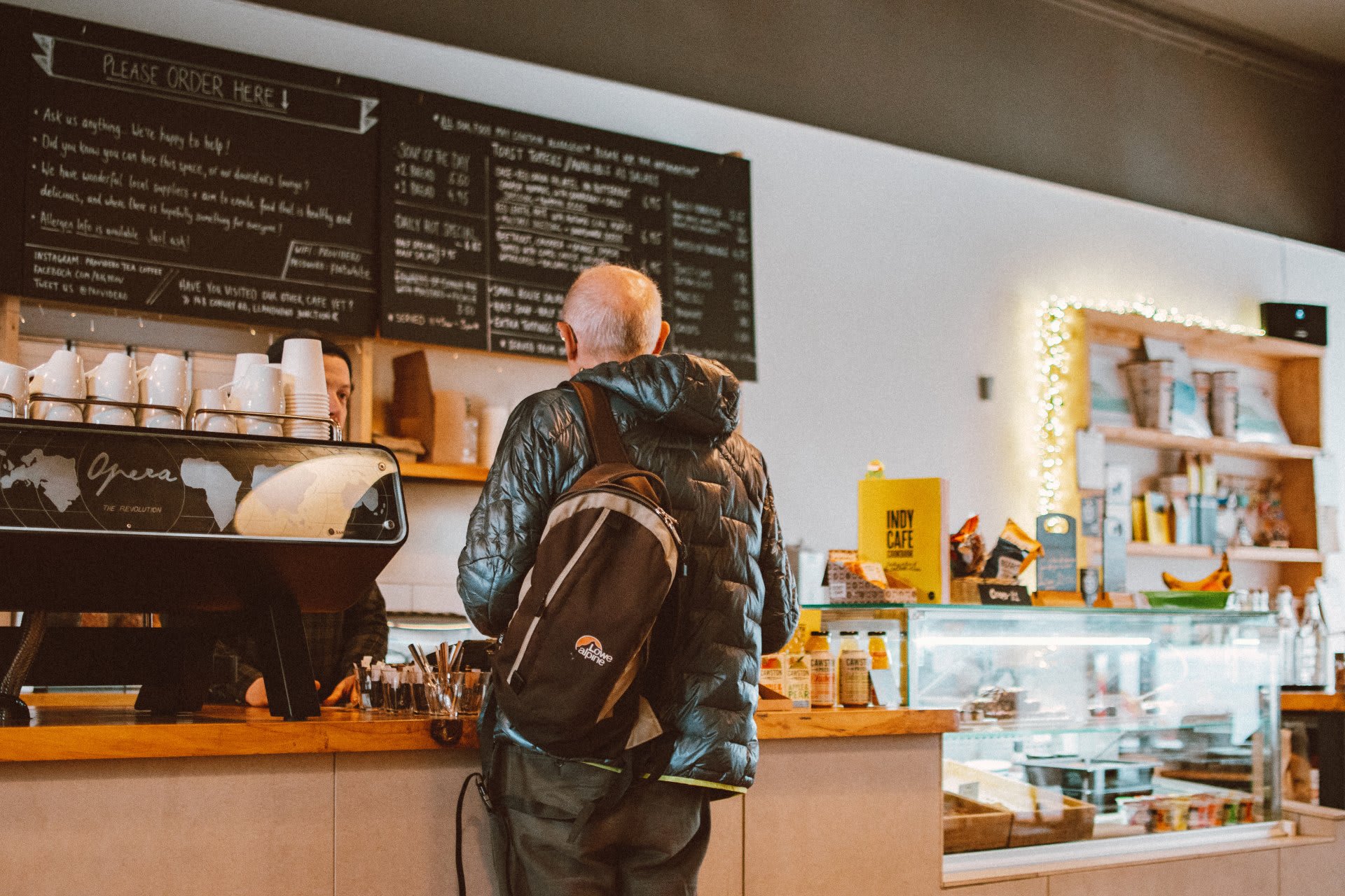 A customer with a backpack ordering at a café counter