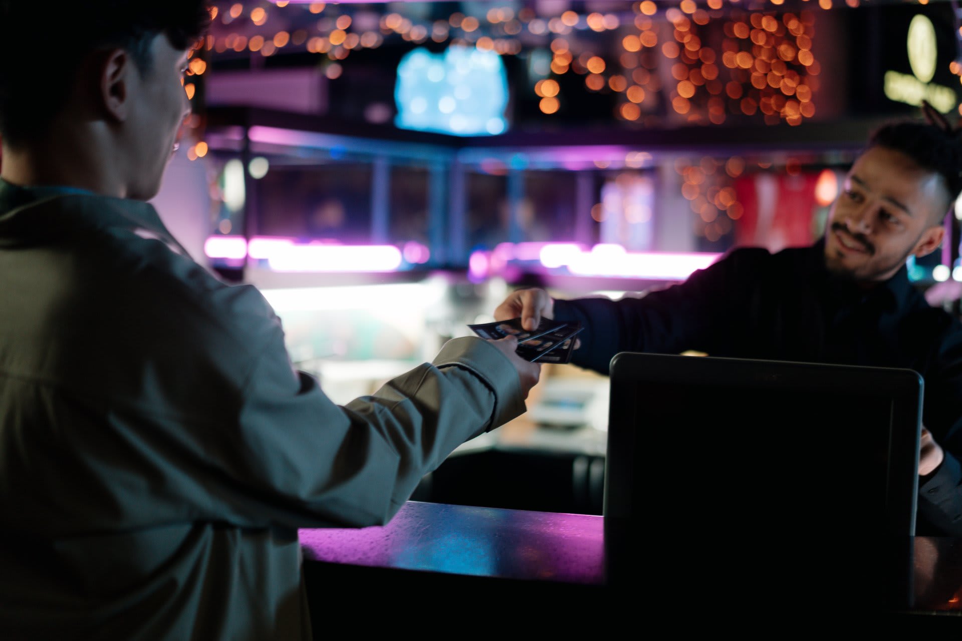 A customer handing a card to a bartender to pay