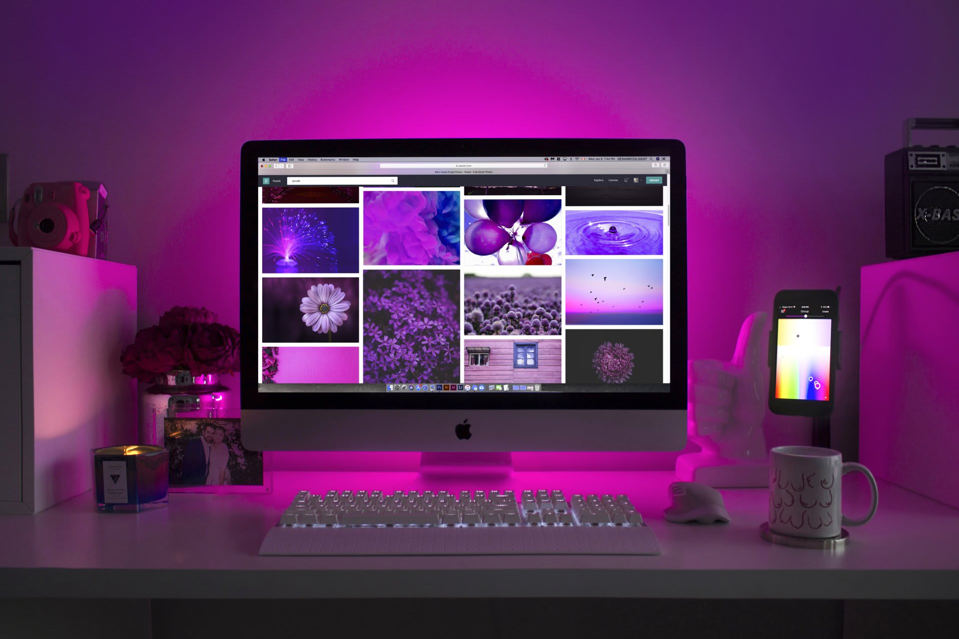 A desktop computer with a website on screen, on a desk lit in pink