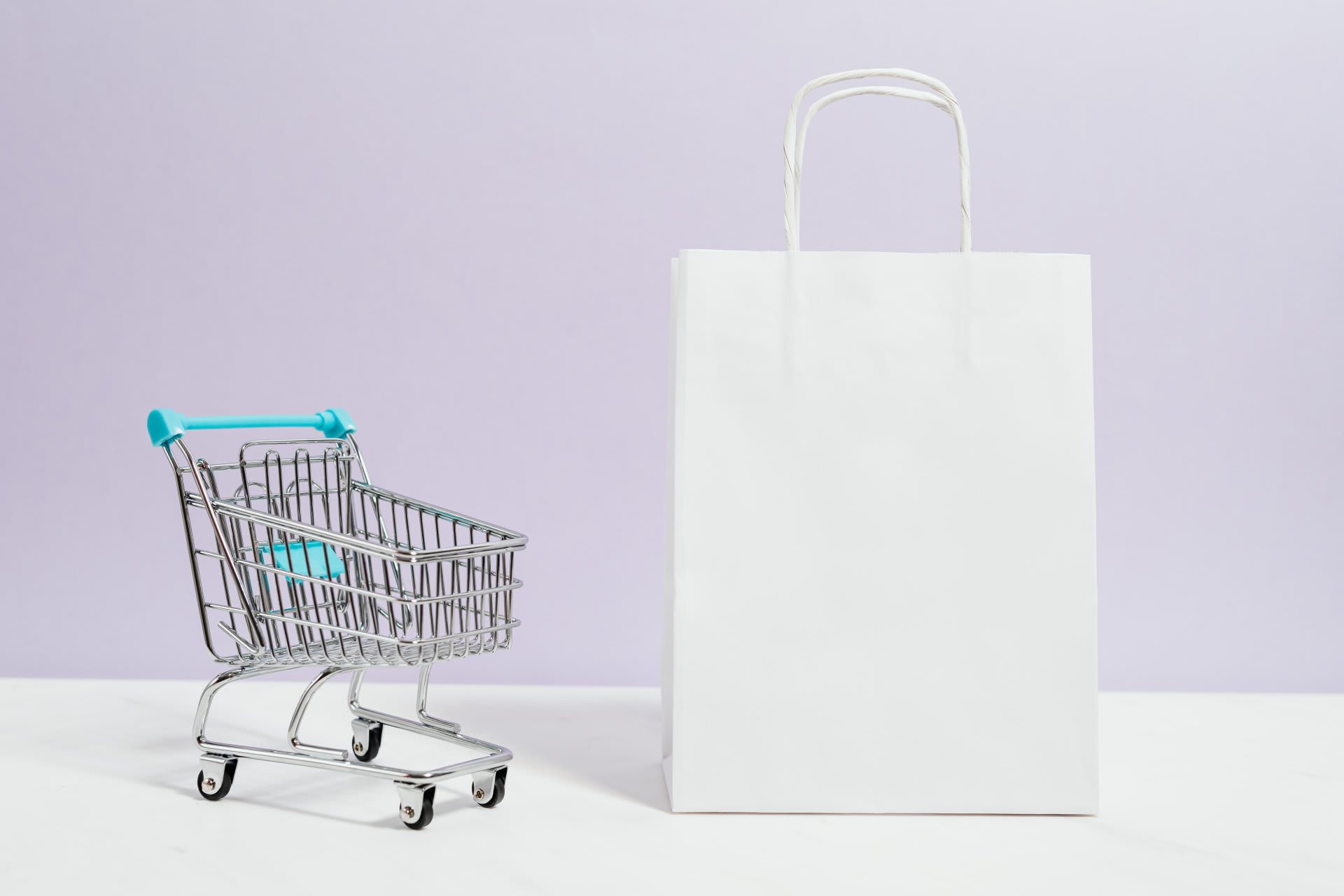 A small shopping cart beside a white shopping bag