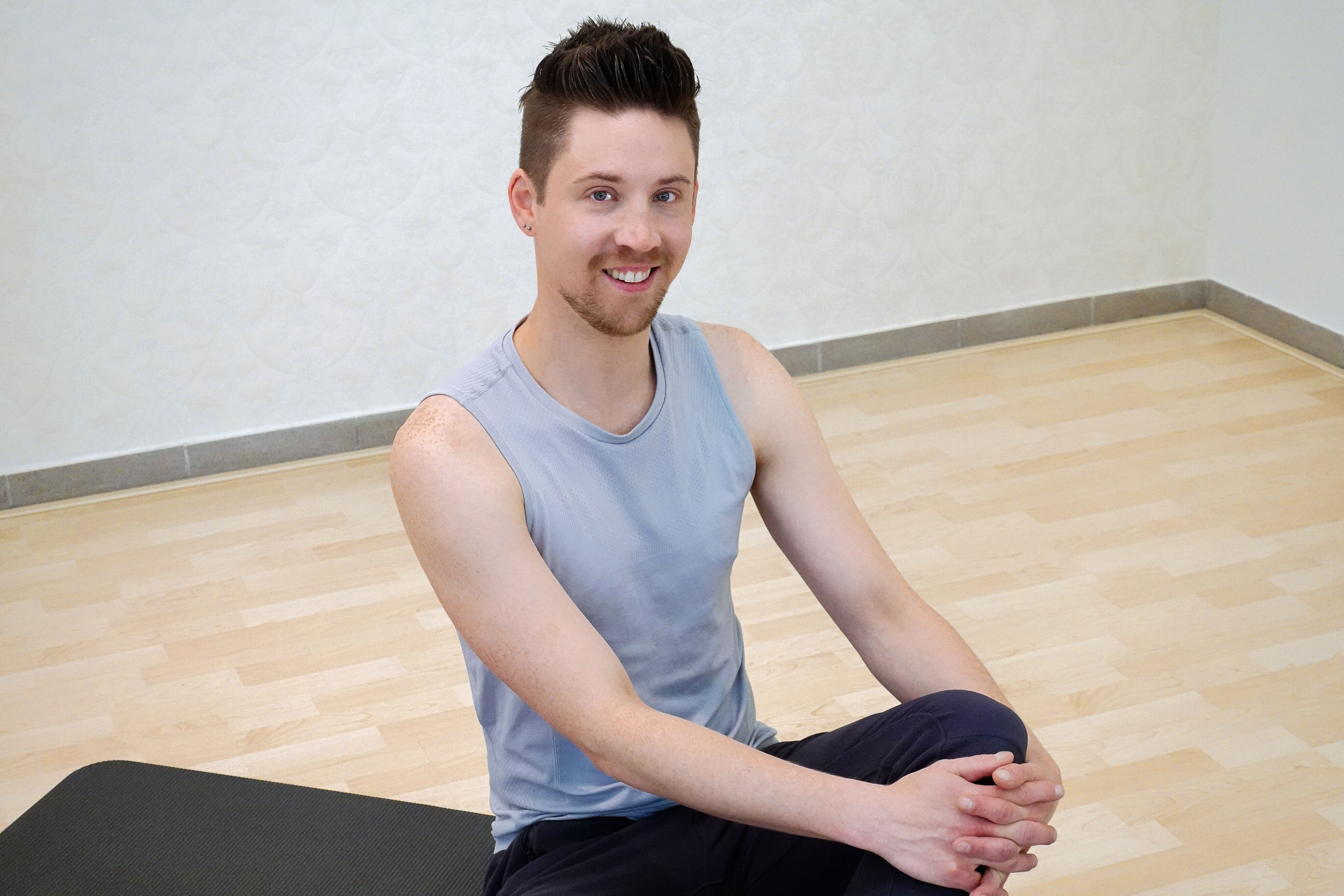 Ein Mann sitzt in Sportkleidung und lacht