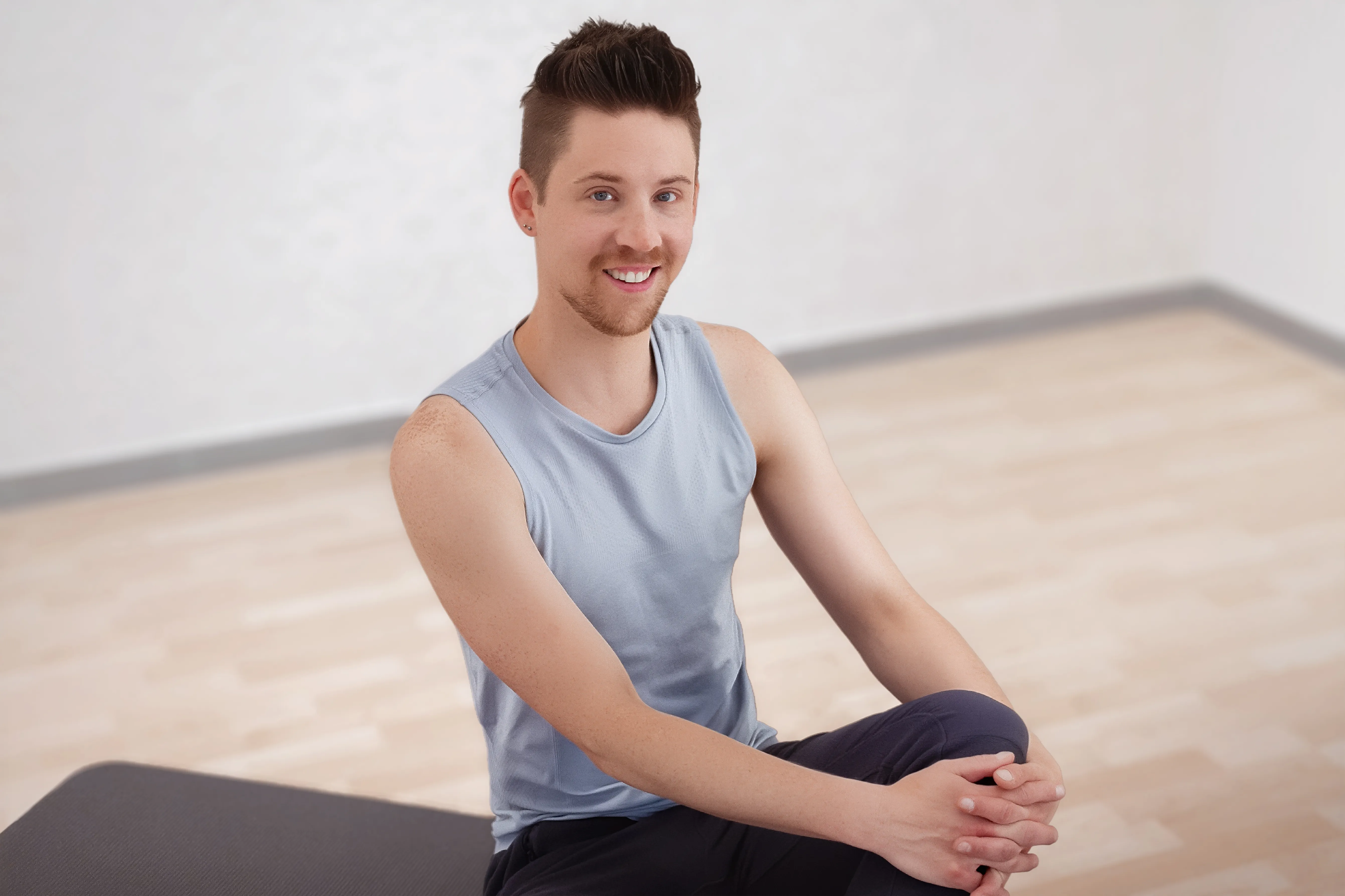 Ein Mann sitzt in Sportkleidung und lacht