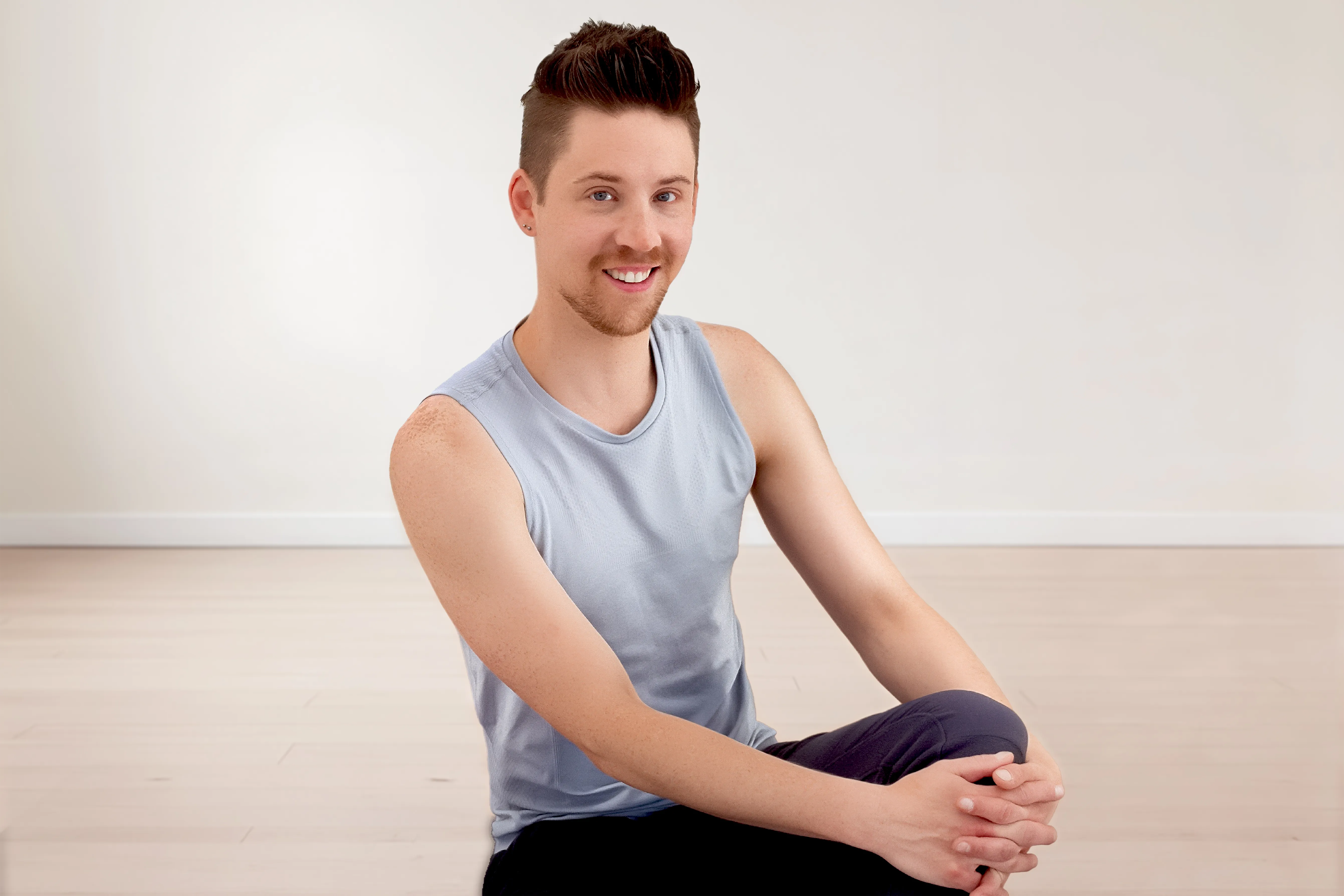 Trainer Fabian sitzt lächelnd auf der Pilates Matte im Pilates Men Kurs