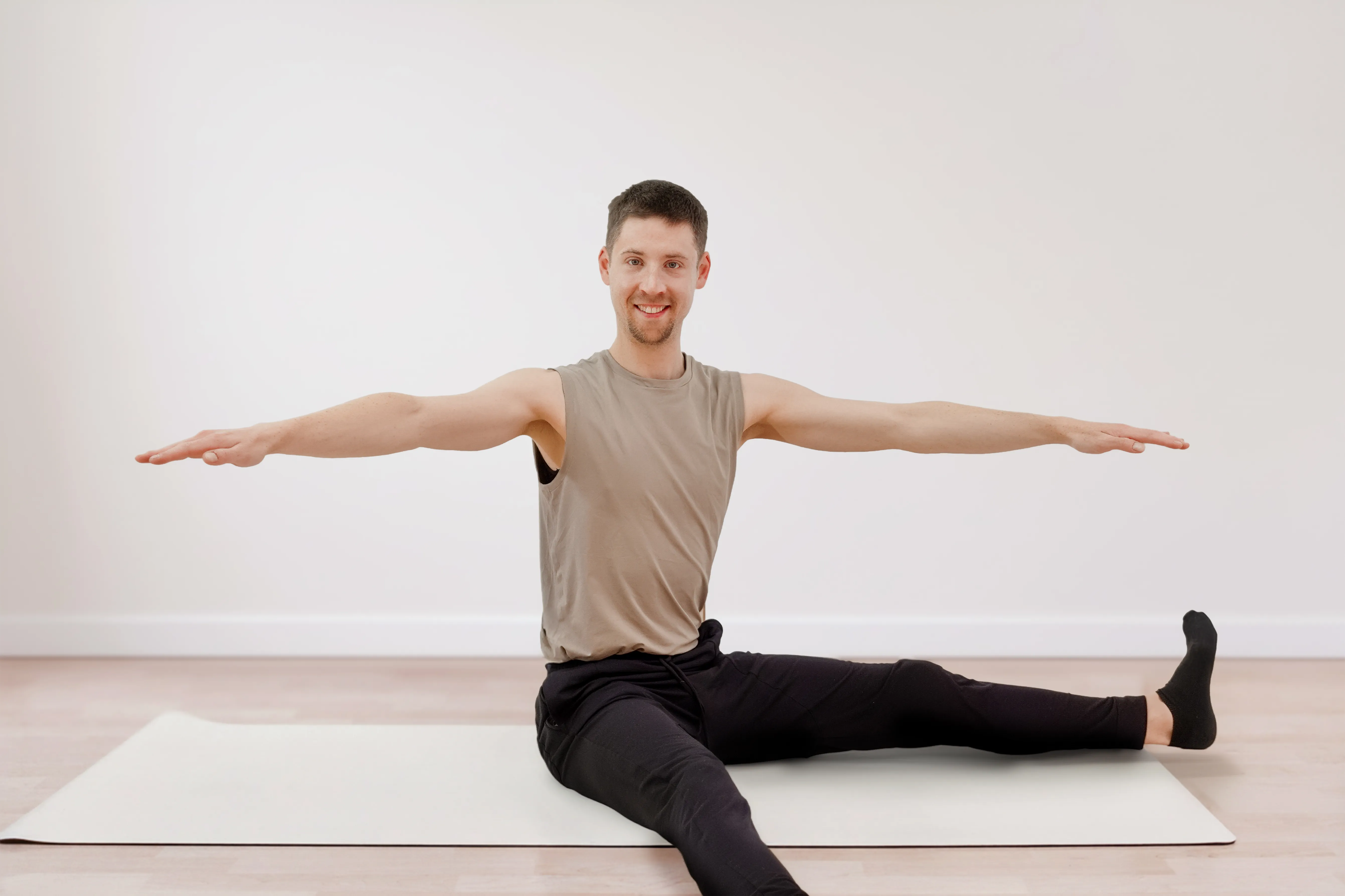 Trainer Fabian macht eine Pilates Twist-Übung auf der Matte im Express Pilates Kurs
