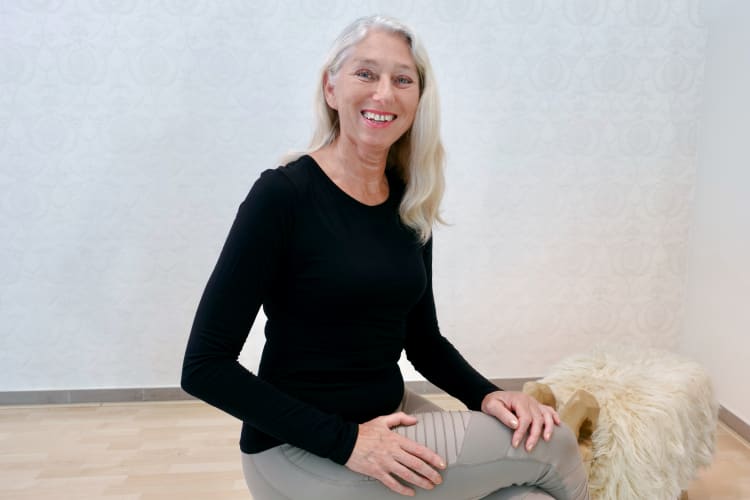 Eine Pilates Trainerin sitzt auf einem Hocker